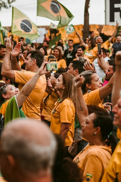 Uma multidão vestida predominantemente de amarelo se reúne na rua, com pessoas erguendo os braços e bandeiras brasileiras. Quando o pertencimento a um grupo se sobrepõe à reflexão individual, ideias e discursos podem ser reproduzidos sem o necessário questionamento de suas consequências