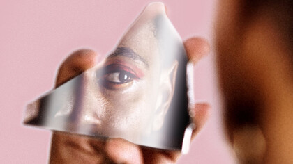 Persona de género fluido reflejada en un fragmento de espejo