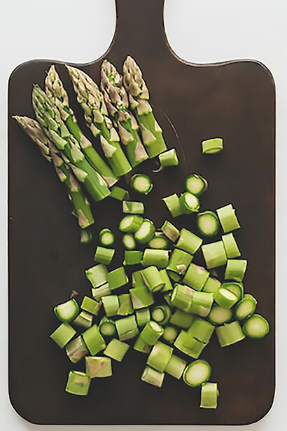 A rustic cutting board becomes a canvas for the artful pairing of asparagus on bread, capturing the essence of a delectable dish that balances flavors and textures with an aesthetic appeal