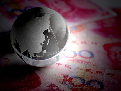 Chinese yuan bills and coins arranged next to a glass globe, representing China's economic influence