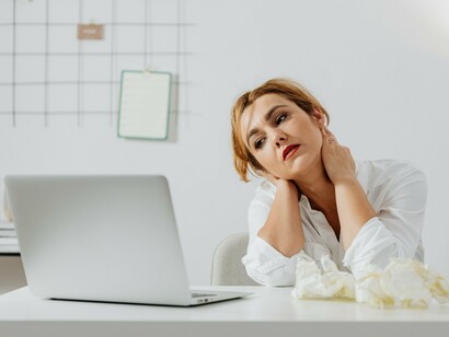 A woman staring down at her workspace with a troubled expression, reflecting the hesitation that keeps people from moving forward