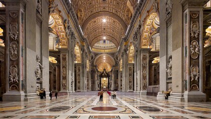 La navata centrale della Basilica di San Pietro si apre come un immenso spazio solenne e luminoso, scandito da colossali pilastri e ornato da marmi policromi e mosaici dorati, che guidano lo sguardo verso l’altare papale. Foto di Nate Bergin. Basilica di San Pietro, Città del Vaticano