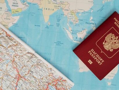 A passport resting beside a world map, symbolising the planning and preparation behind international migration