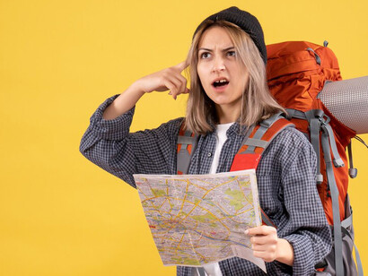 Front view of a woman traveler with a backpack, examining a map as she navigates her journey