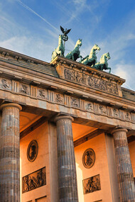 The Brandenburg Gate in Berlin, Germany, stands as a symbol of resilience, its ancient stone columns bathed in the warm glow of a Berlin sunset, reminding us of the city's journey from division to unity