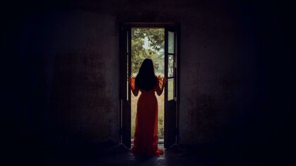 Standing at the threshold between darkness and light, she pauses in the stillness of becoming