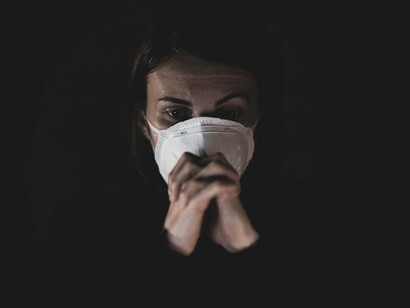 A woman, masked amid the pandemic, appears lost in deep sadness and despair
