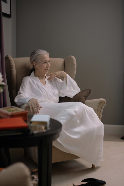 An elderly woman sitting in an armchair at home