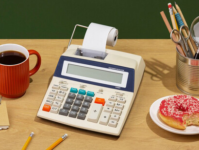 A desk setup with a calculator, donut, and coffee, perfect for visualizing food ingredient pricing and cost calculation in café operations