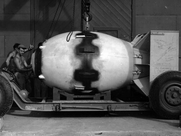 A Fat Man aparece em primeiro plano, destacando o formato volumoso e a complexidade de uma das primeiras armas nucleares utilizadas em uma guerra. Em 9 de agosto de 1945, uma bomba desse tipo foi lançada sobre Nagasaki, marcando um momento decisivo na história da tecnologia militar e da humanidade