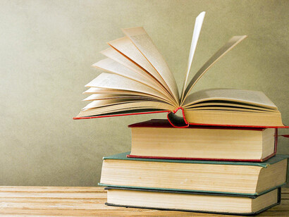 An open book on a pile. In education, knowledge helps us create our own opinion and views on life and society as a whole