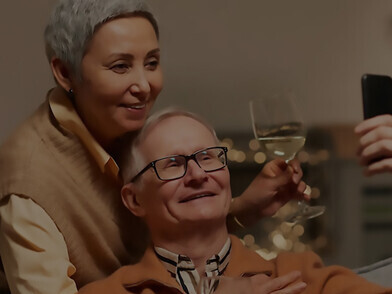 An elderly couple in Europe is drinking wine at their home