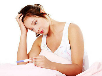 A young woman holding her pregnancy test, looking distressed and uncertain