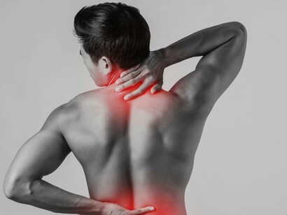 A man grabs his neck and lower back, highlighting common hotspots for morning aches