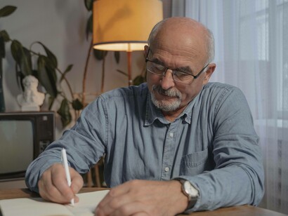 A senior citizen scribbling down his expenses as he's now in the silver economy bracket 