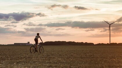 Teenager rides in a field with a windmill in the distance