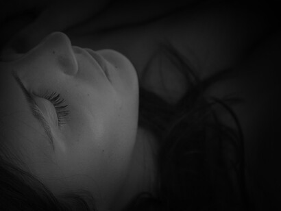 A woman closing her eyes trying to sleep while combating ADHD