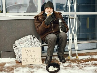 A homeless man eating a simple meal outdoors in winter, representing the fundamental importance of food in the fight against poverty