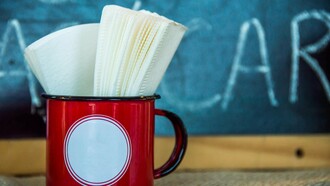 Guardanapos guardados numa caneca vermelha, à espera de uso como tantas presenças silenciosas que ocupam espaço na rotina sem realmente cumprir a função