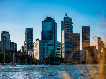 The Brisbane River flowing before the modern city skyline, representing the thread that binds Brisbane’s past and present