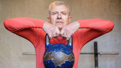 An elderly man lifting a heavy kettlebell, symbolizing longevity, healthspan optimization, and physical resilience