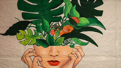 A painting of a girl with green and red flowers emerging from her head, symbolizing the concept of love as a force for personal growth and mental health