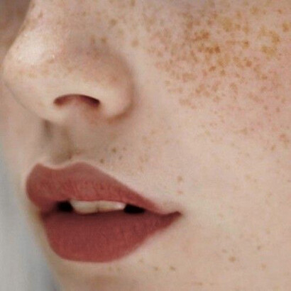 A teenage girls pale freckled skin with her lips painted red