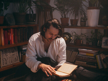 A man reading a book of poetry on a vintage red carpet