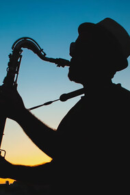 Silhouette of a man playing saxophone during sunset