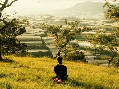 A person sitting alone on a hill overlooking the city, quietly reflecting in a peaceful moment