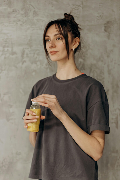 Woman holding a bottle of juice after a gym session, reflecting the healthy lifestyle often promoted by fitness influencers