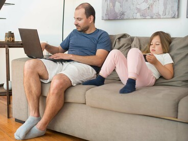Pai e filha utilizam dispositivos eletrônicos juntos em um ambiente doméstico. A cultura digital modifica a relação com os textos e acelera a circulação das informações, mas não elimina a necessidade de atenção e interação