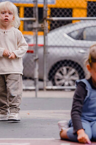 Two young friends bring a touch of nostalgia to the playground as they carefully sketch out their hopscotch grid, eager to relive the timeless joy of this classic game