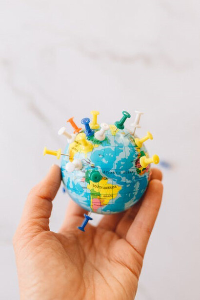 A person delicately cradles a small globe in the palm of their hand