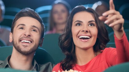 Una pareja en el cine hablando y comiendo palomitas