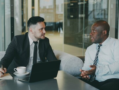 Two professionals engaged in a focused workplace discussion, representing the importance of employers addressing the financial needs of their workforce