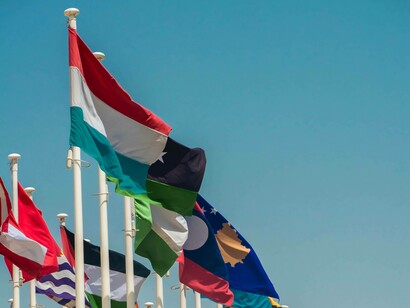 Flaggen verschiedener Länder auf weißen Fahnenmasten