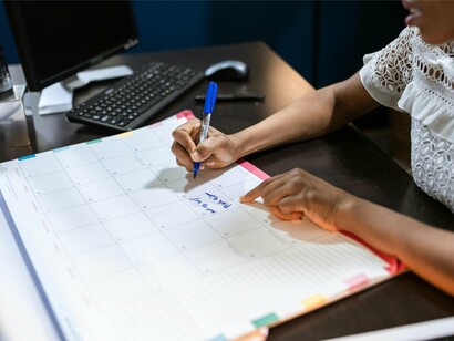 Mulher faz planejamentos em calendário. O primeiro item adicionado por ela foi aprender a fazer escolhas conscientes