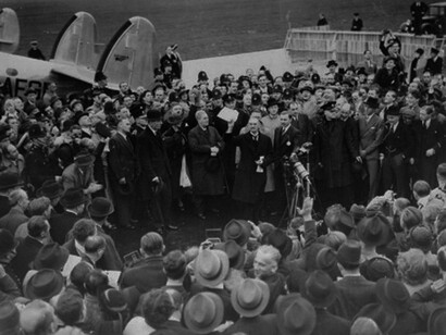 Neville Chamberlain holds the paper signed by both Hitler and himself on his return from Munich