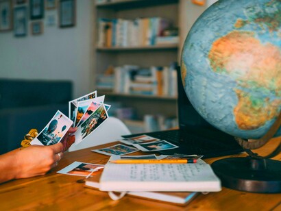 Jovem observa suas fotos. O migrante é obrigado a confrontar não apenas a cultura do novo lugar, mas também suas próprias concepções e preconceitos. Nesse processo, a saudade se torna um sentimento ambivalente, que remete ao que foi perdido, mas também à possibilidade de transformação e criação