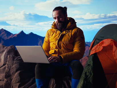 A freelancer immersed in work while surrounded by towering mountains, representing autonomy in the digital age