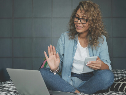 Image of a woman in denim jeans using her computer on the bed