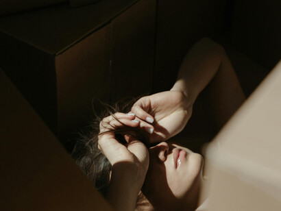 A woman among the boxes, too exhausted to finish the process of moving out
