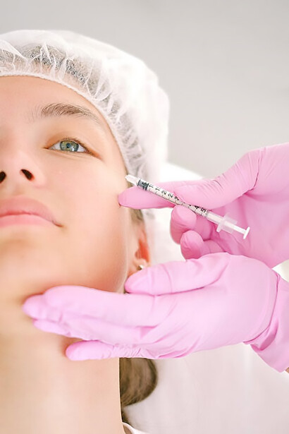 Unveil a new glow with a young woman receiving expert filler application from a doctor adorned in pink gloves, creating a fresh and radiant facial allure