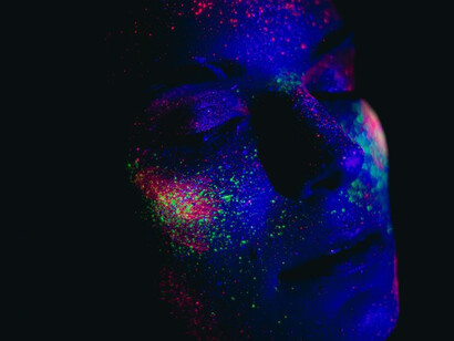 A woman's visage adorned with a vibrant array of colored powders, creating a stunning and artful transformation
