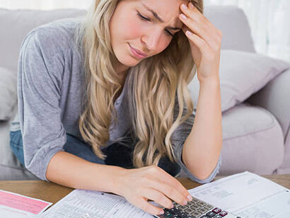 A young, pensive woman reflecting on her debt and the burden of heavy taxes