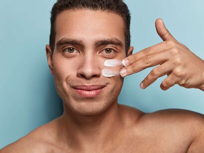 A young man taking care of his personal face care with daily cream