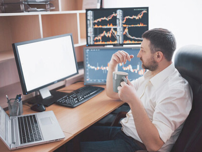 A stockbroker in a shirt monitors display screens in a trading room, analyzing US stock market trends, forex, and financial data amid rising economic instability and market risks