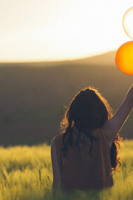 Woman holding balloons in a field