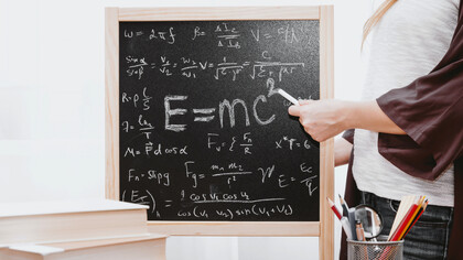 Una profesora de física enseña la fórmula de la energía en una pizarra